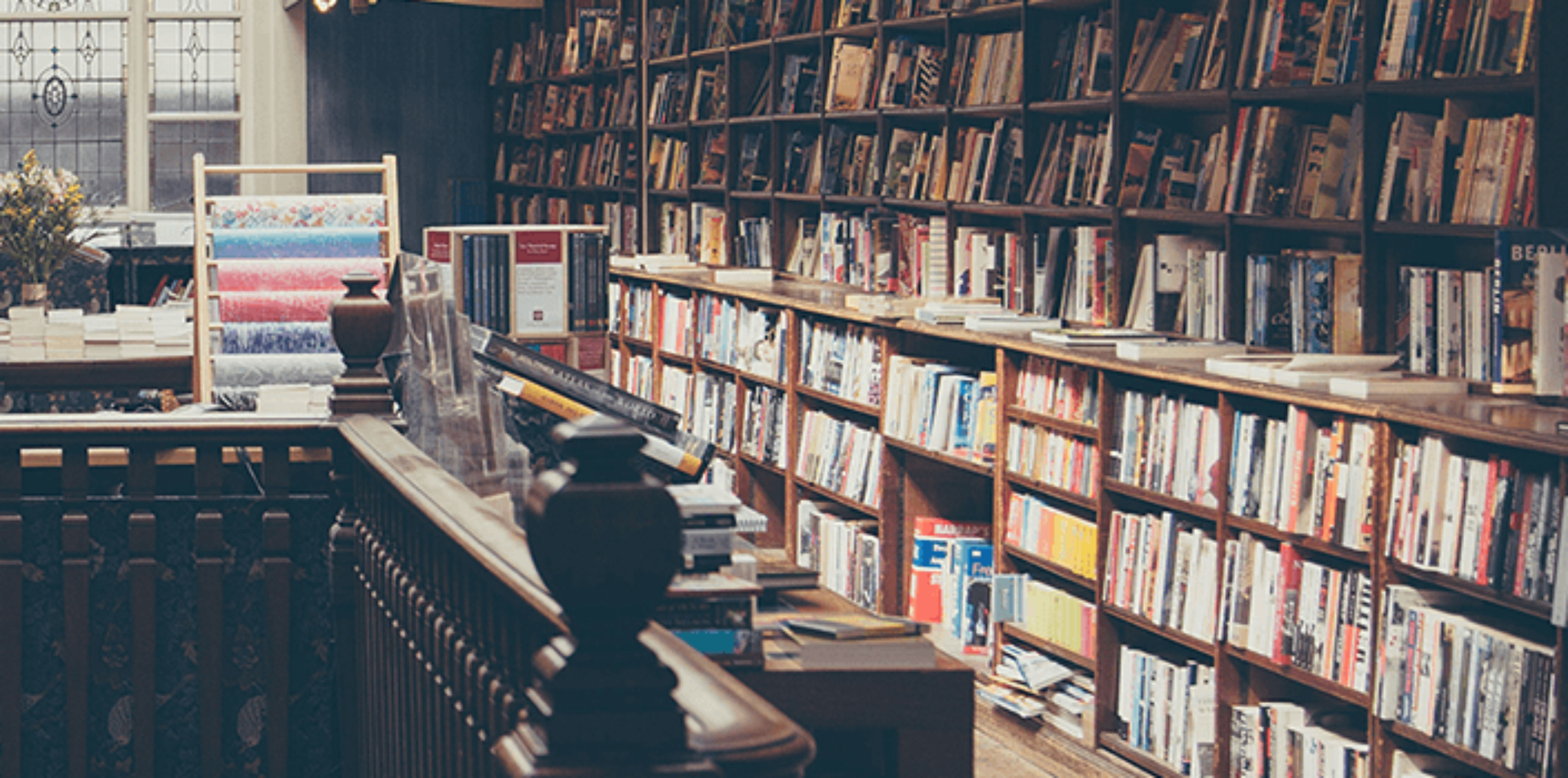 Charming book store with wood railing, stained glass window, and shelves full of books