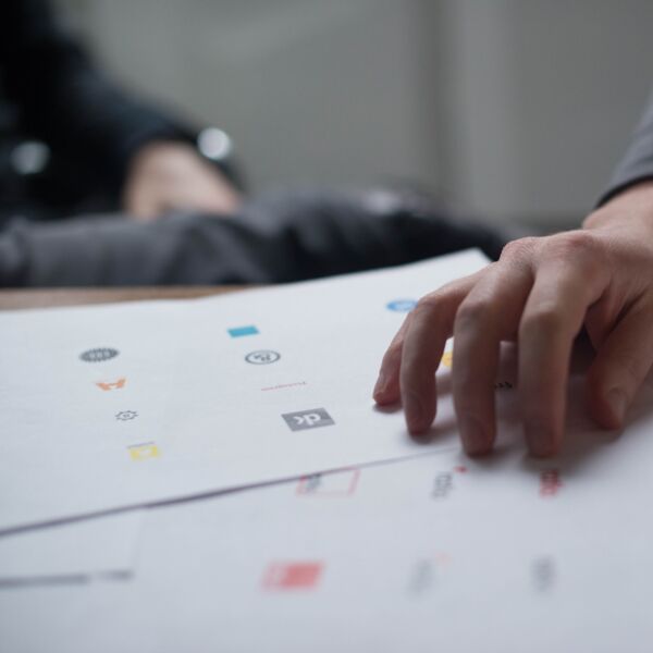 Hand hovering over logo designs during a design review