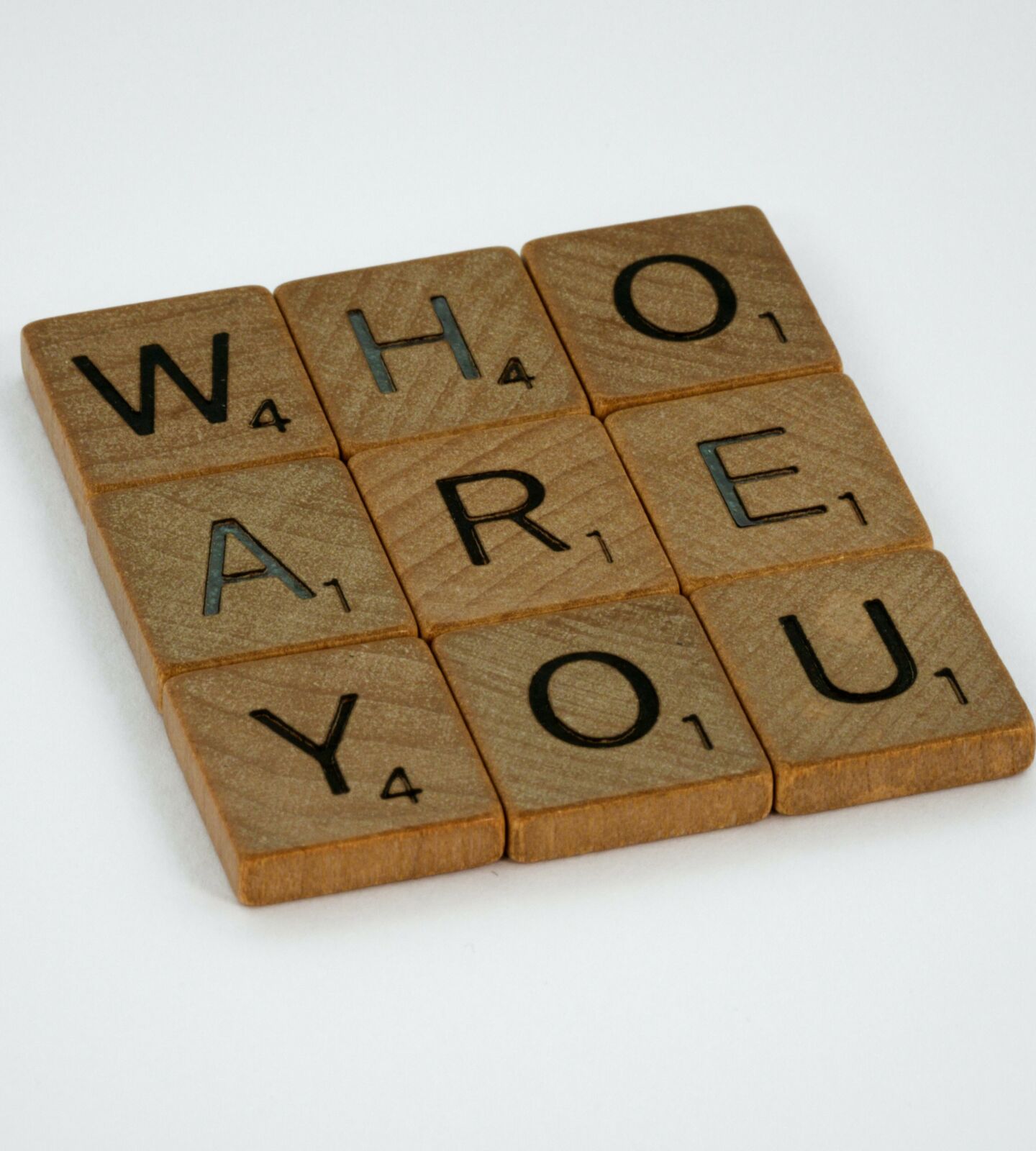 Tiles from the game, Scrabble. They spell Who Are You and are arranged in a 3x3 square.