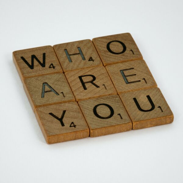 Tiles from the game, Scrabble. They spell Who Are You and are arranged in a 3x3 square.