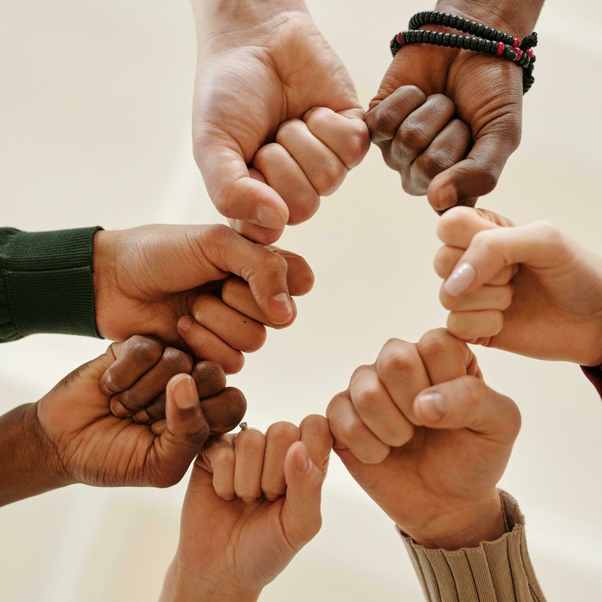 Group of hands of various skin colors coming together to fist bump.