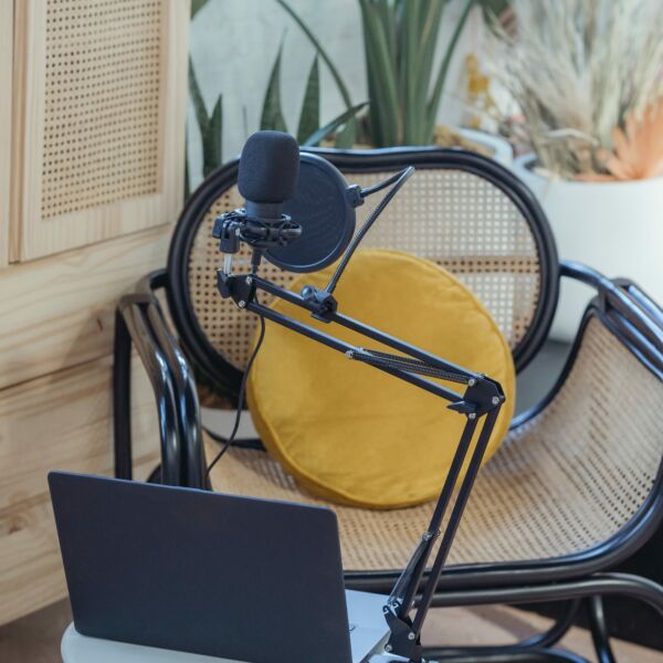 Photo of podcast setup with laptop, microphone arm with mic, and chair