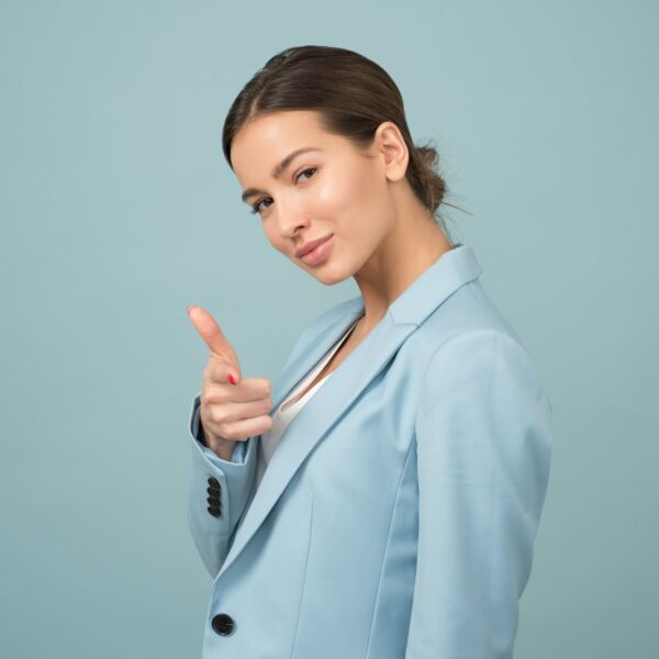 Woman wearing blue shawl lapel suit jacket pointing at you and looking very confident