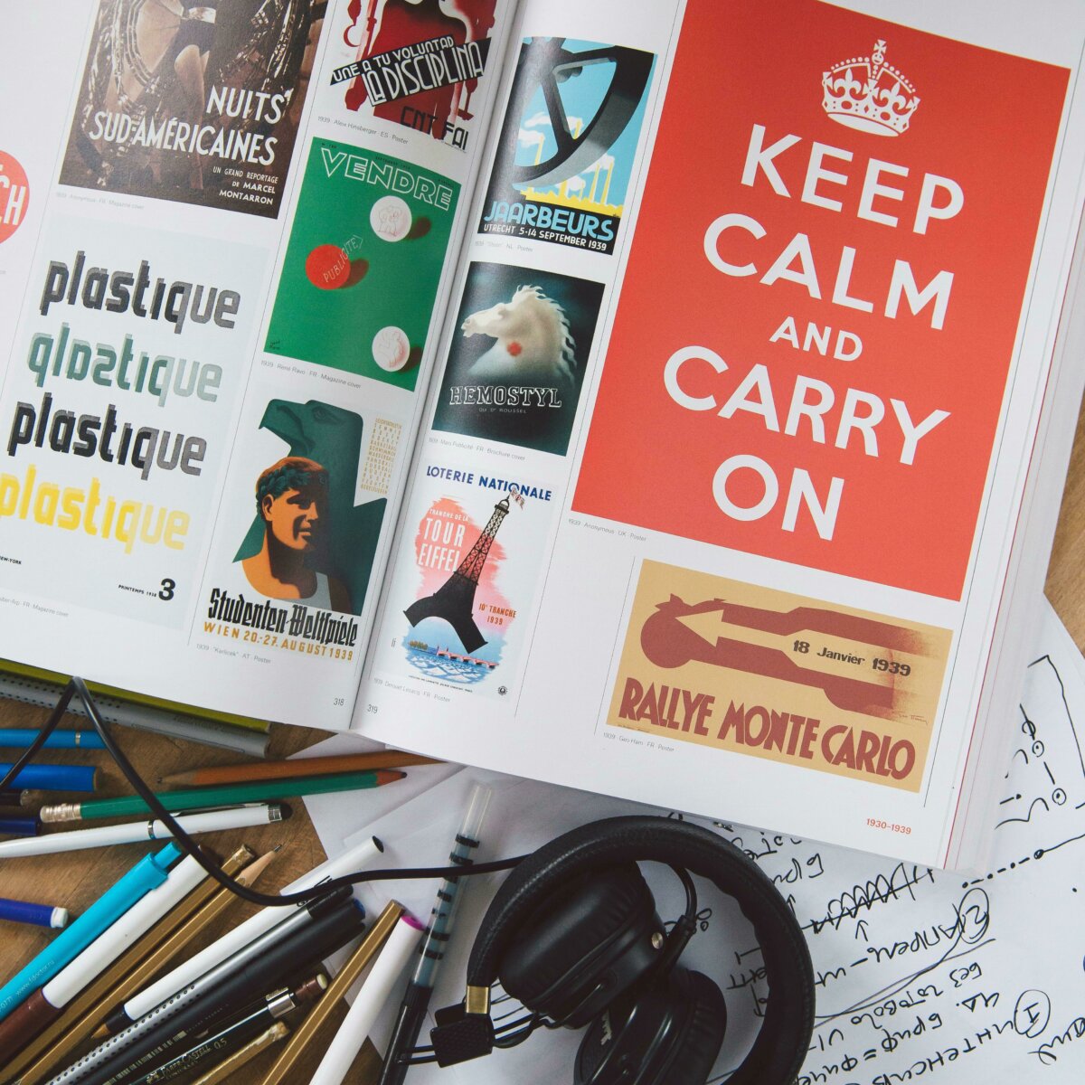 Top down image of a design magazine on a desk next to different color pens and pencils.